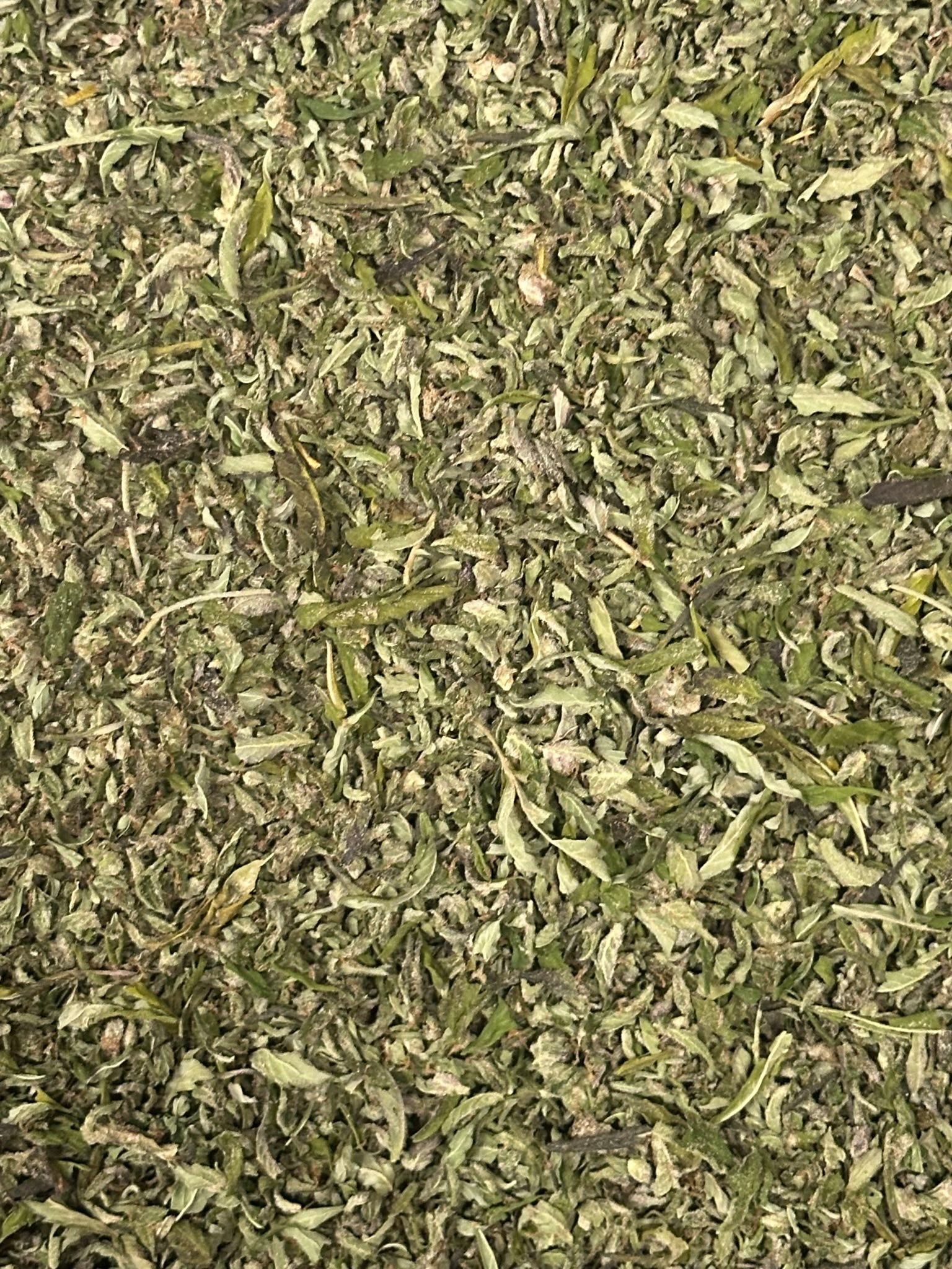 RS-11 cannabis trim from The Green Leaf Cannabis, featuring small sugar leaves and broken buds with visible trichomes—ideal for making pre-rolls, extracts, or infusions. Hybrid strain known for balanced effects and a sweet, fruity aroma.